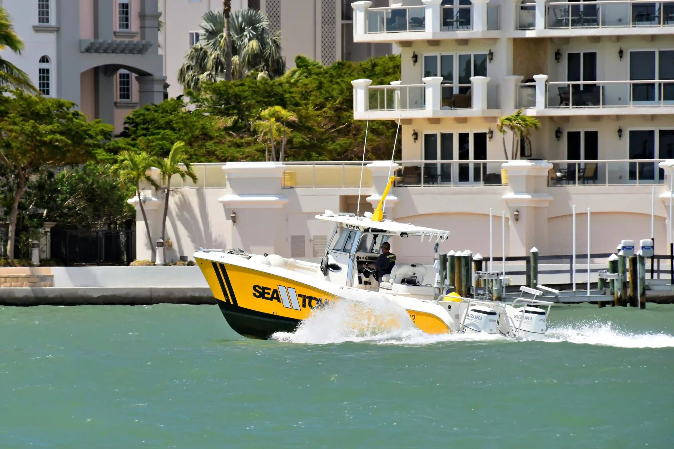 Yellow Sea Tow boat speeding across the water in Sarasota, Florida with luxury condos in the background