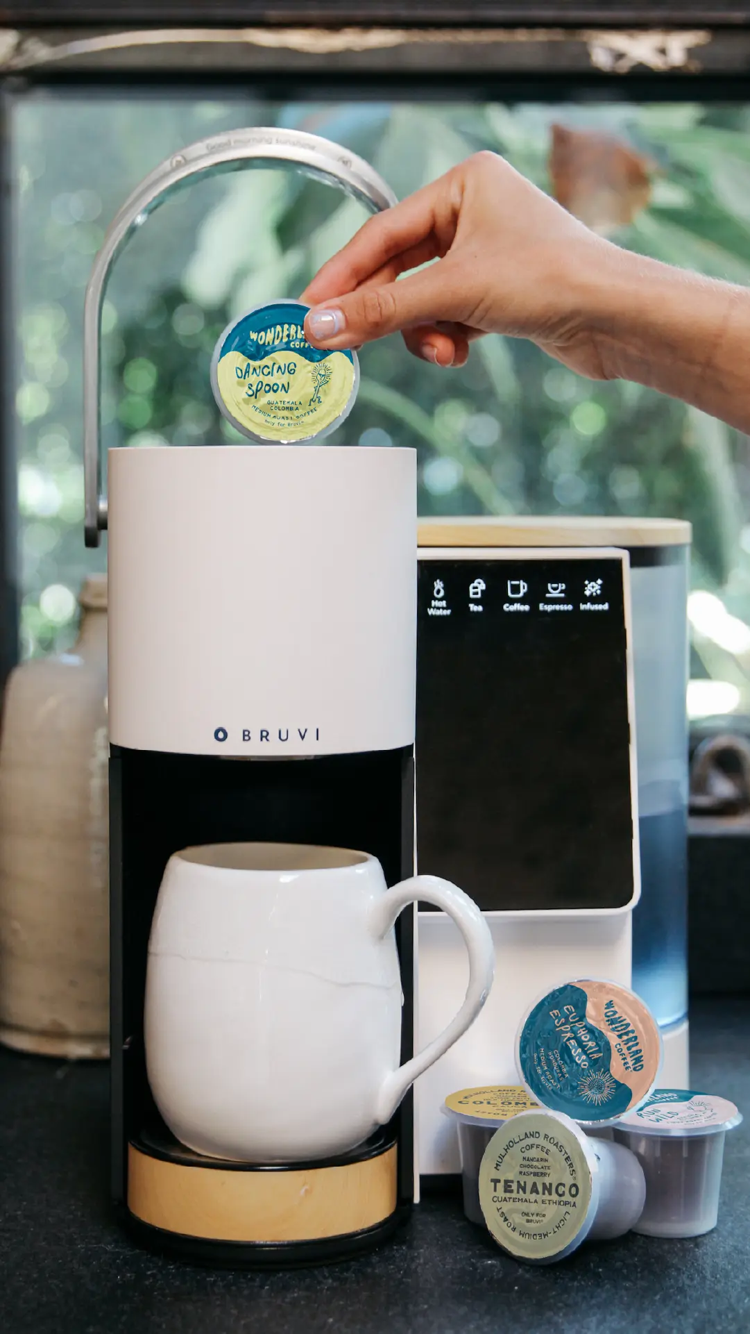 Bruvi single-serve coffee maker on a kitchen counter with multiple drink options including espresso, iced coffee, black coffee, and matcha.