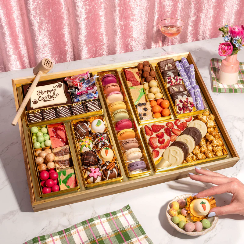 Boarderie Easter dessert charcuterie board with macarons, chocolates, candies and spring-themed sweets arranged on a serving tray