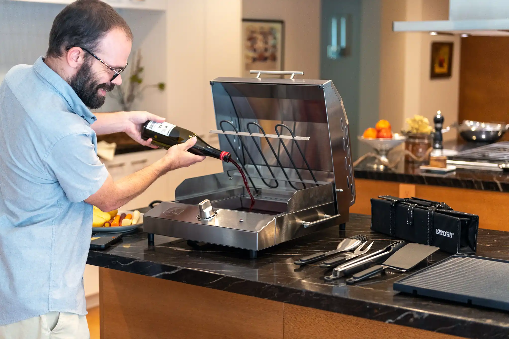 Kenyon G2 Grill portable electric grill showing non-stick grate and concealed heating element and man preparing infusion tray