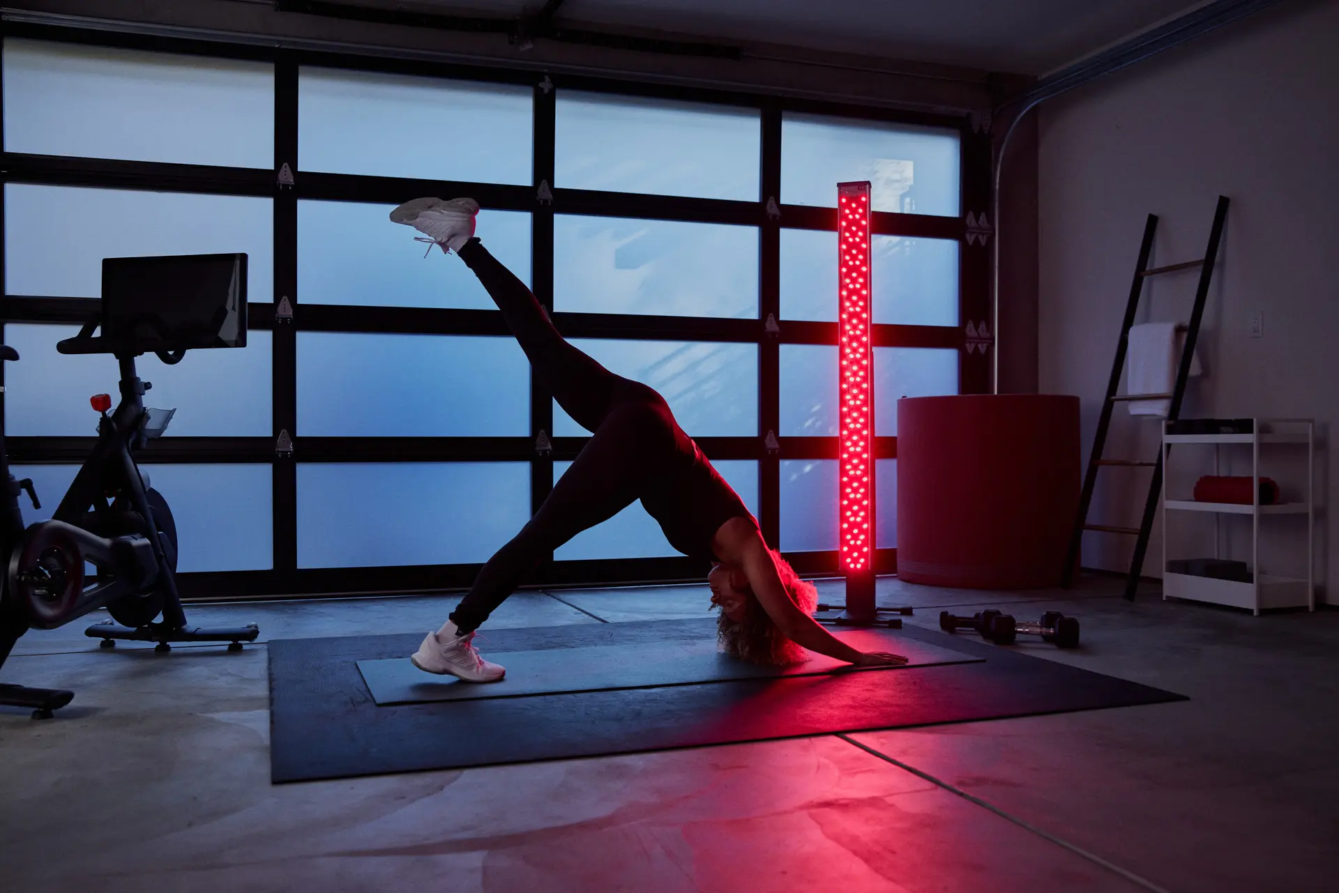 woman working out in home gym with clearlight red light in the backround