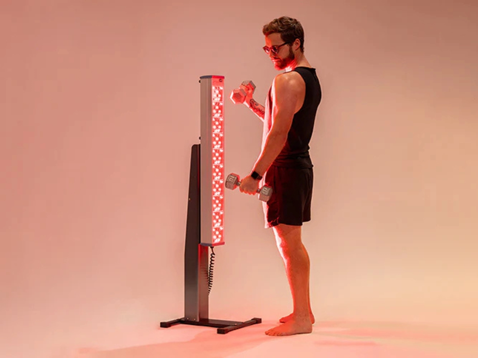 Man standing near Clearlight red light holding handles and working out
